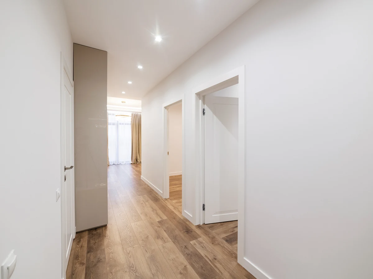 hallway-painting-clean-white-corridor-exeter-decorators Clean white hallway with light walls and a wooden floor leading to open doors