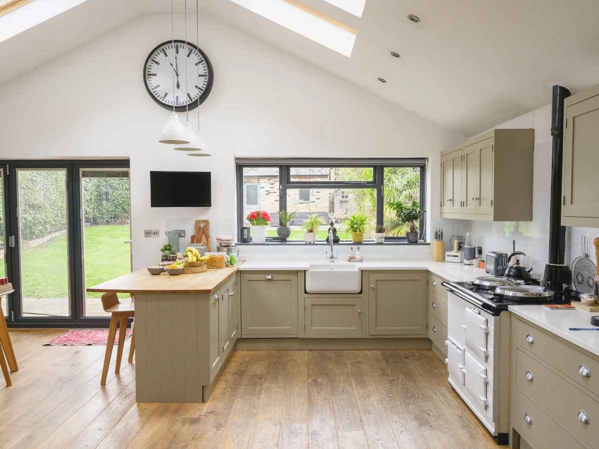 kitchen-painting-large-open-plan-exeter-decorators Open-plan kitchen with sage green cabinets, a central island and a vaulted ceiling
